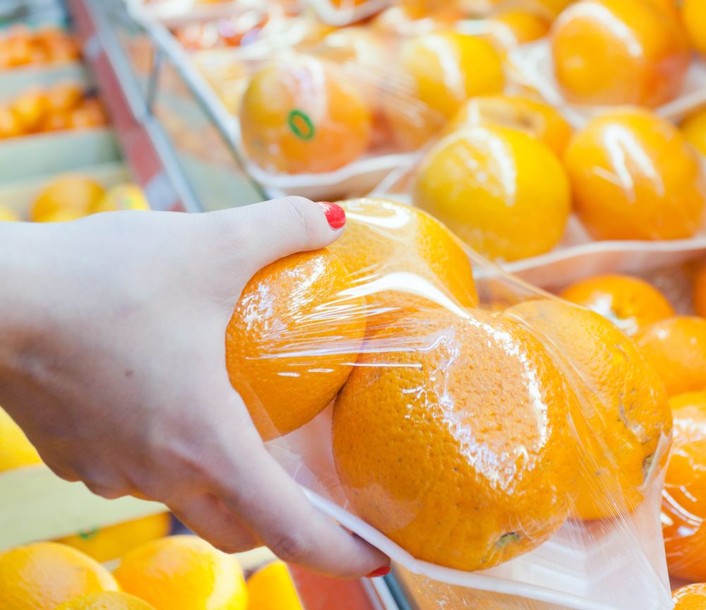Image of packaged orange with woman hand in the supermarket